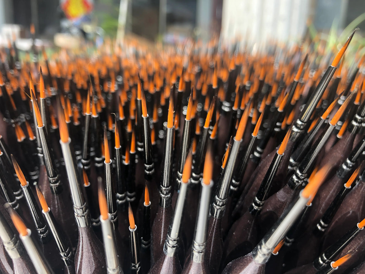 Close up of FTR brushes with orange bristles and black handles.