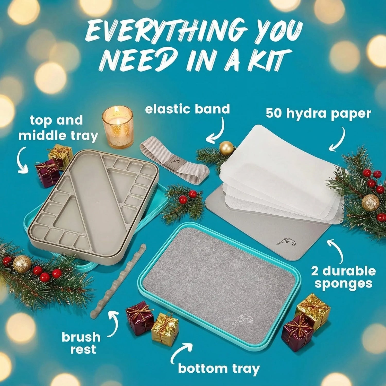 Wet and Dry wet palette kit with top and middle tray, elastic band, hydra paper, sponges, brush rest, and bottom tray on a blue background with Christmas decorations.